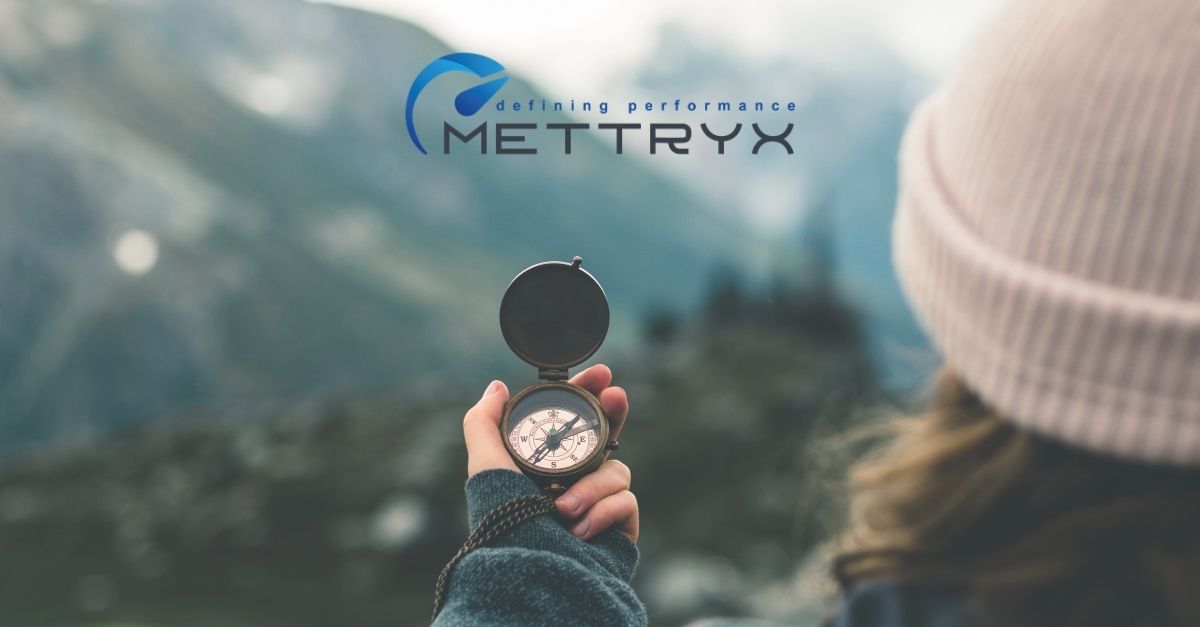 Lady using a compass to navigate Mettryx logo in the distance. Forward Looking