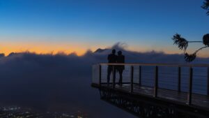 Couples standing on a viewpoint in the mist above mountains. Insights.